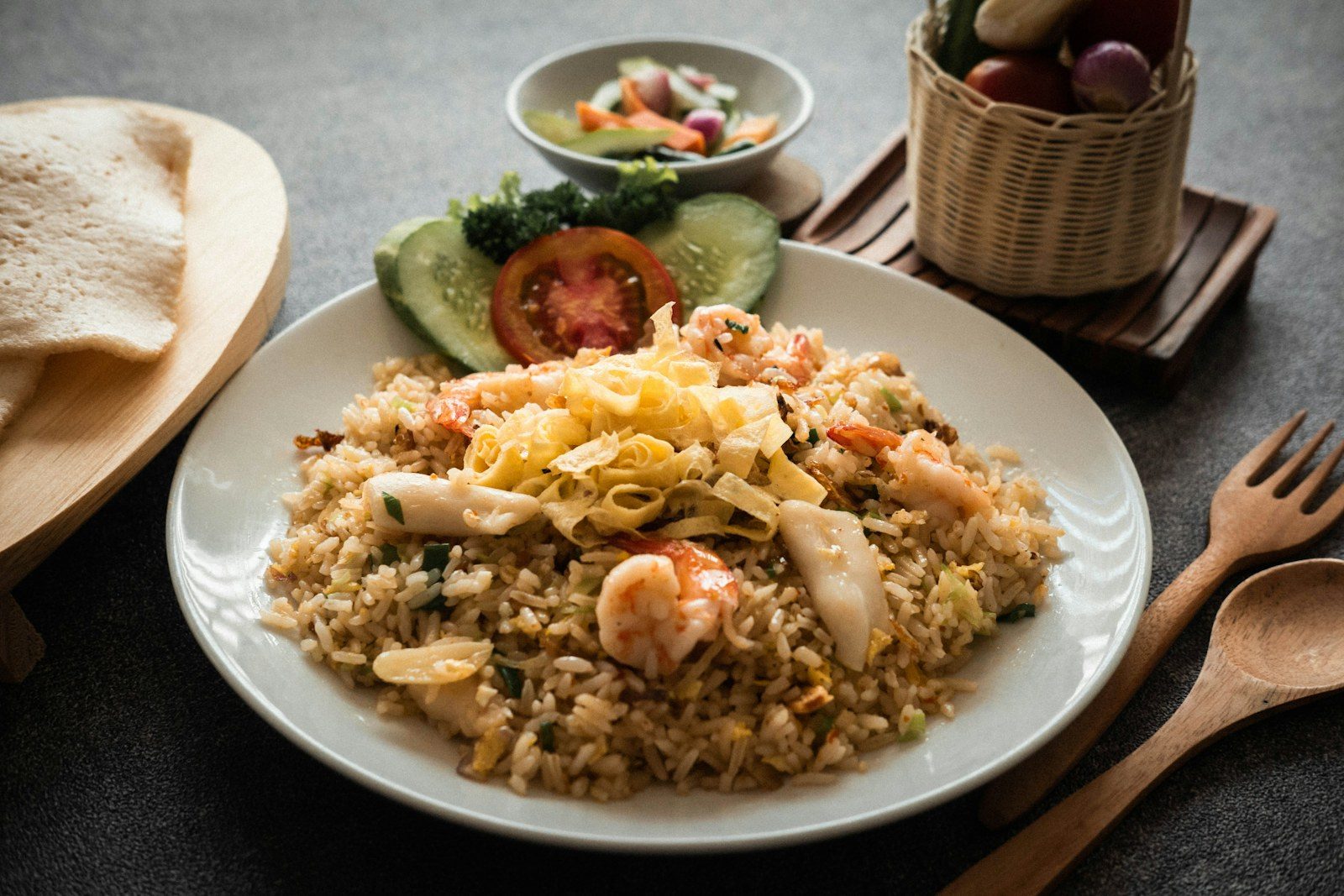 talerz ciemnego nasi goreng z jajkiem sadzonym, krupukiem i plasterkami ogórka